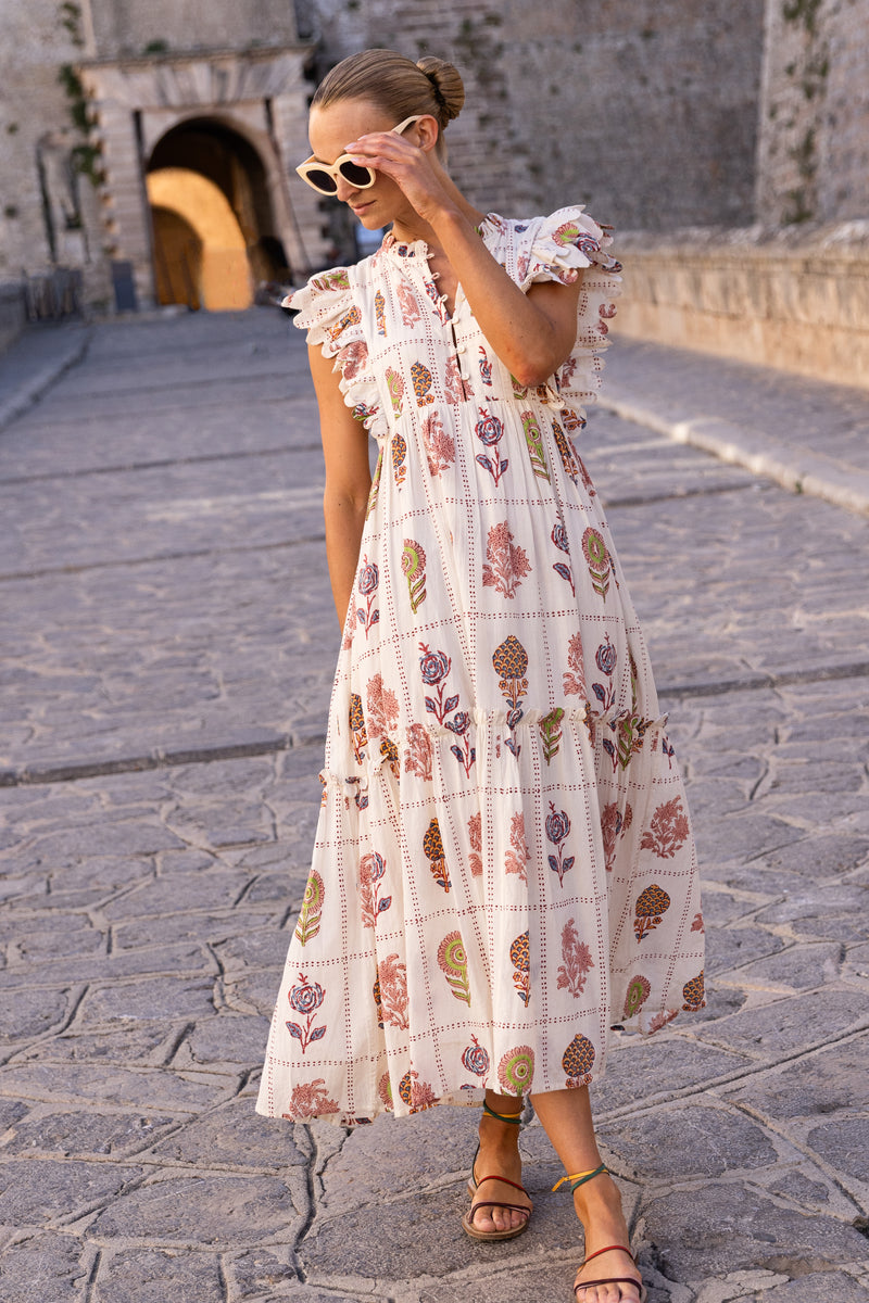 Woman in a floral maxi dress walking on a stone pathway.